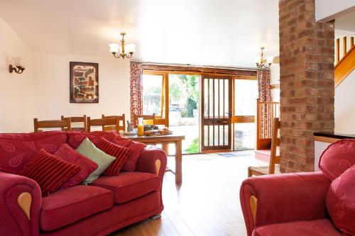 a living room with a red couch and a table at Pintle Cottage in Charlbury