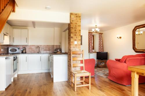 a kitchen and living room with a red couch at Pintle Cottage in Charlbury