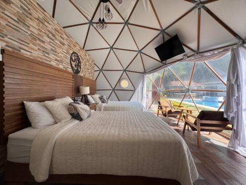 a bedroom with two beds in a room with a large window at Glamping en Valle de Bravo in Valle de Bravo