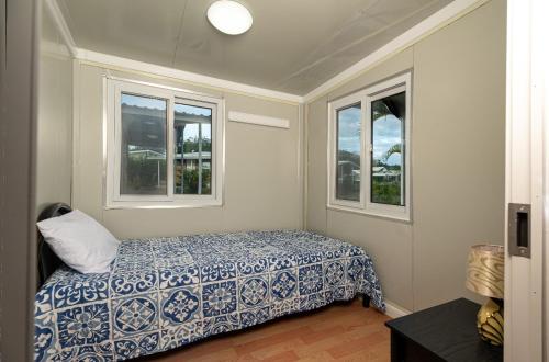 a bedroom with a bed and two windows at Tiny Homes Tamarindo in Tamarindo