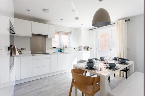 a kitchen with white cabinets and a table with chairs at Heath Reach - Just a short distance to Tower Park in Poole