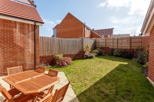 a small backyard with a wooden table and chairs at Heath Reach - Just a short distance to Tower Park in Poole