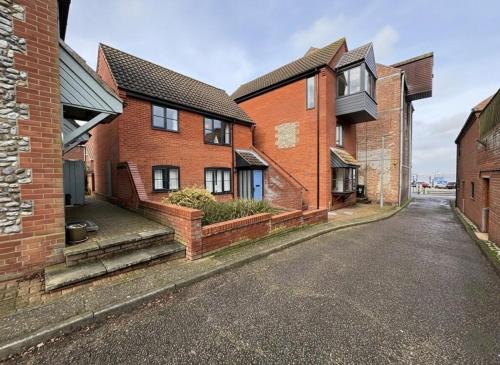 a row of brick houses on an empty street at AnchorageWells Harbour Apartment in Wells next the Sea