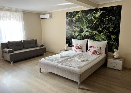a bedroom with a bed and a large painting on the wall at Napfény Apartman in Makó