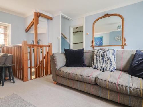 a living room with a couch and a mirror at Riverdance Cottage in Lyme Regis