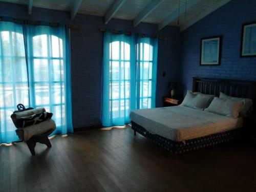 a bedroom with a bed and blue walls and windows at blue beach in Rocha
