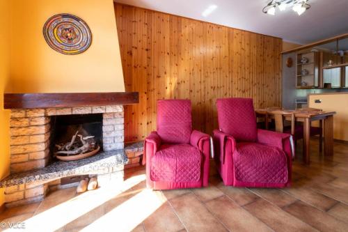 a living room with two pink chairs and a fireplace at La Casetta di Pino in Varenna