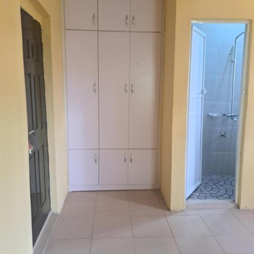 a bathroom with white cabinets and a walk in shower at Trendy Terrace in Benin City