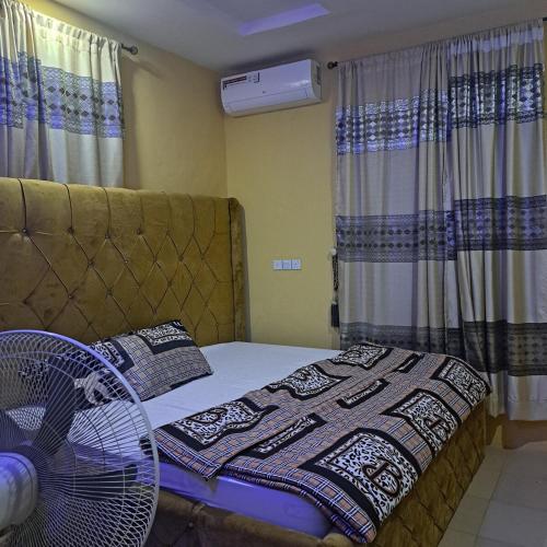 a bedroom with a bed with a fan and curtains at Trendy Terrace in Benin City