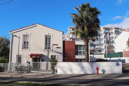 ein weißes Gebäude mit einer Palme und einem Hydranten in der Unterkunft Hotel Abelia in Montpellier