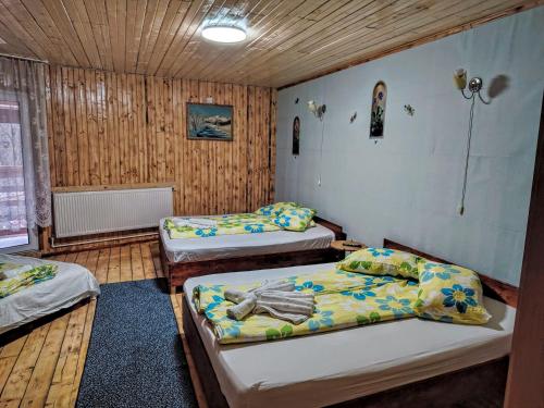 two beds in a room with wooden walls at Casa Tudor Turda in Turda