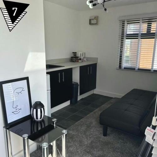 a living room with a black couch and a kitchen at The Mayfair Lodge & Family Suite in Hartlepool