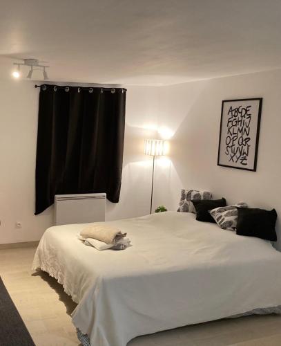 a bedroom with a large white bed with a black curtain at Apartment avec cours in Bonny-sur-Loire