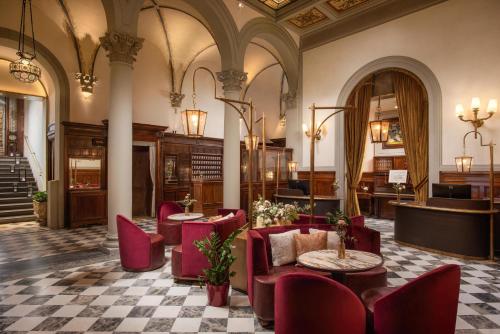 a lobby with red chairs and tables in a building at Porta Rossa Hotel Firenze, Colbert Collection in Florence