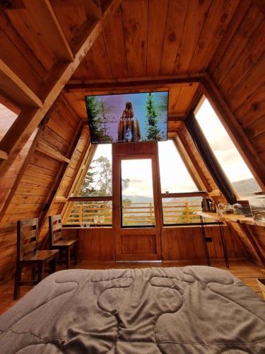 a bedroom with a large window and a tv in a cabin at Sisuma Ecolodge in Güicán