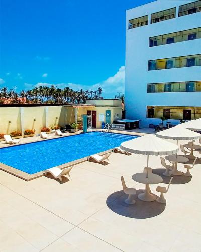 a swimming pool with chairs and umbrellas next to a building at Golden Beach Hotel in Fortaleza
