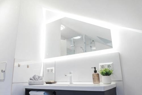 a white bathroom with a sink and a mirror at Dreiländer Blick Apartments in Lörrach
