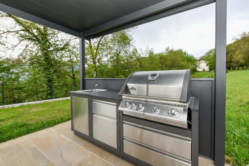 a grill on a patio with a view of a field at Agriturismo Hegemone in Tremosine Sul Garda
