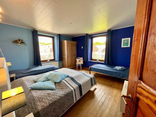 a bedroom with a bed and blue walls and windows at La Méliraude in Daverdisse