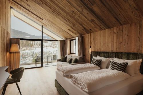 a bedroom with two beds and a large window at Luxury B&B August in Ortisei