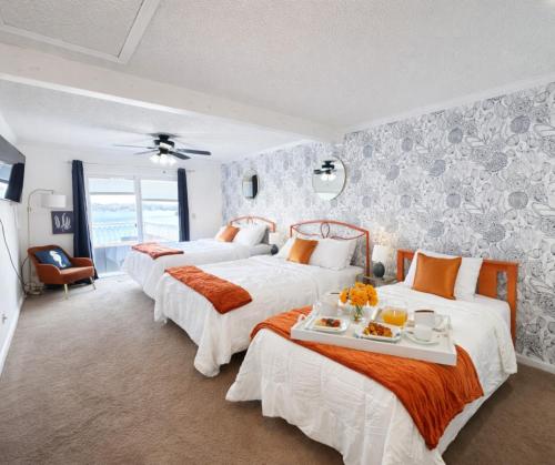 a bedroom with three beds with orange and white sheets at Sunset and Chill Lakefront 3 Bed 2 Bath Hottub, Firepit Dock in Lake Ozark