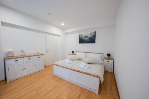 a white bedroom with a bed and wooden floors at Central Gerolstein Panorama Apartment in Gerolstein