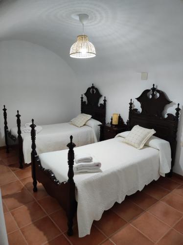 a bedroom with two beds with white sheets and a chandelier at El refugio de Águeda in Gorafe