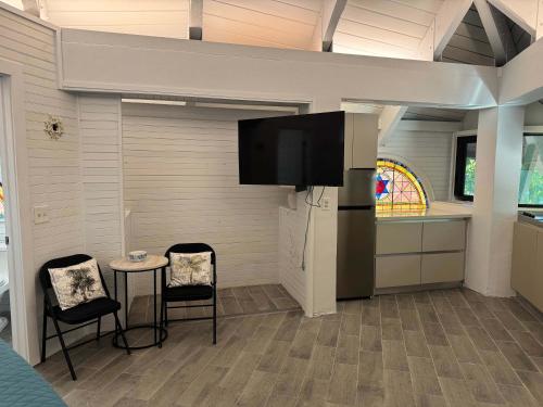 a kitchen with a tv and two chairs and a table at Treehouse Private Village at Barnacle Resort in Big Pine Key