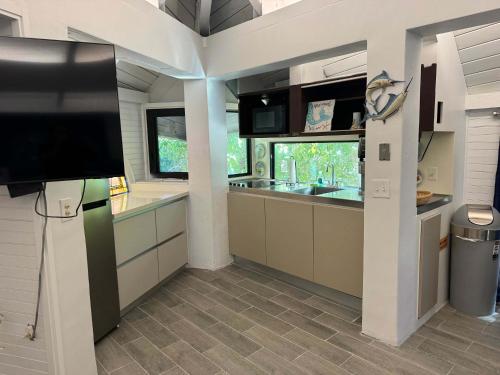 a kitchen with a flat screen tv and a counter at Treehouse Private Village at Barnacle Resort in Big Pine Key