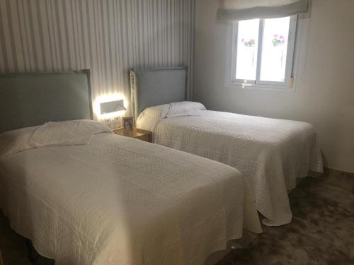 two beds in a hotel room with a window at Atelier de lujo lucena in Lucena