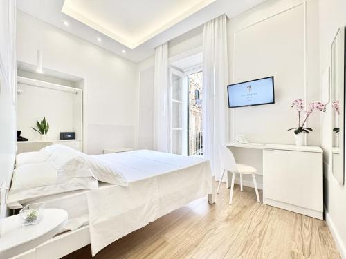 a white bedroom with a bed and a desk at Napoleon in Tropea