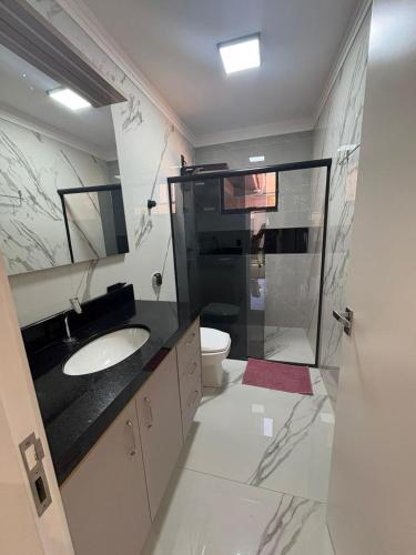 a bathroom with a sink and a toilet and a shower at Casa da Palmeira com Piscina in Piratuba