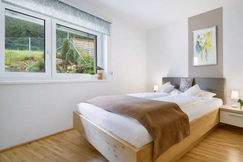 a bedroom with a large bed and two windows at Alpinum Residence Lungau Ferienwohnung mit Garten in Tamsweg