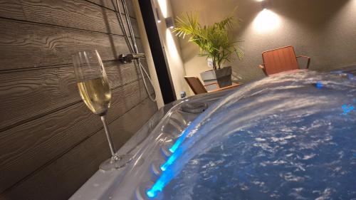 a glass of wine sitting next to a hot tub at Love room- Le Cocon Osé in Autun