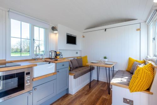 a kitchen with blue cabinets and a table with yellow cushions at 1 Bed in Saltfleetby oc-b30072 in Saltfleetby Saint Peter