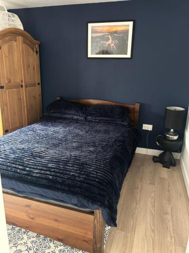 a bed in a bedroom with a blue wall at Swansea Waterfront in Swansea