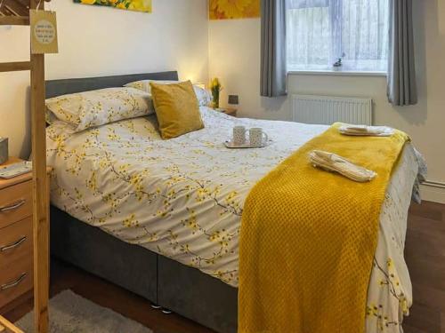 a bedroom with a bed with a yellow blanket on it at Hillside in St Austell