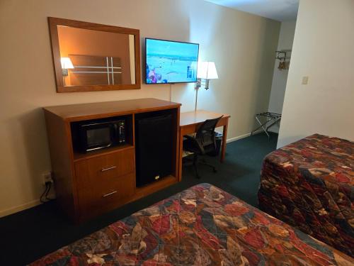 a hotel room with two beds and a desk with a tv at Travelers Lodge Marshall in Marshall