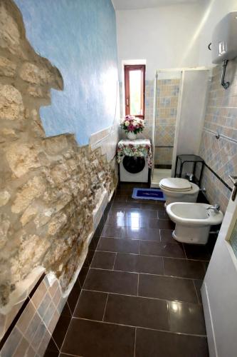 a bathroom with two toilets and a stone wall at Shaka guest house in Giba