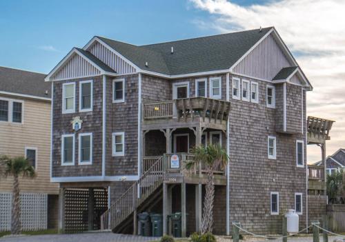 a large brick house with a porch and a balcony at Happy Dog Days - Nags Head MP 11, Ocean View, 50 Yds to Beach, Elevator, Pool, Hot Tub, Pets OK, Flex Stays in Nags Head