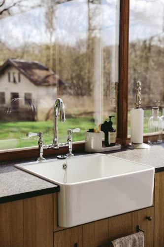 a white sink in a kitchen with a window at Le Gîte du Haras in Falaën