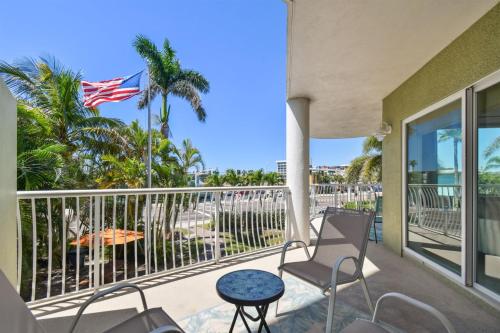a balcony with chairs and an american flag at Sunsets & Coastal Vibes Treasure Island Stay in St. Pete Beach