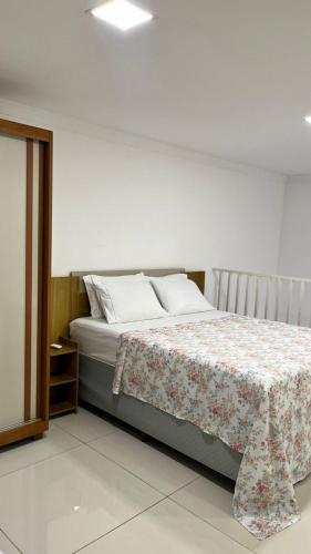 a bedroom with a bed with a floral blanket on it at Casa praia 99 in Serra