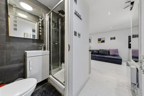 a bathroom with a toilet and a shower and a couch at Studio Flat in Stepney-Limehouse - Central London in London