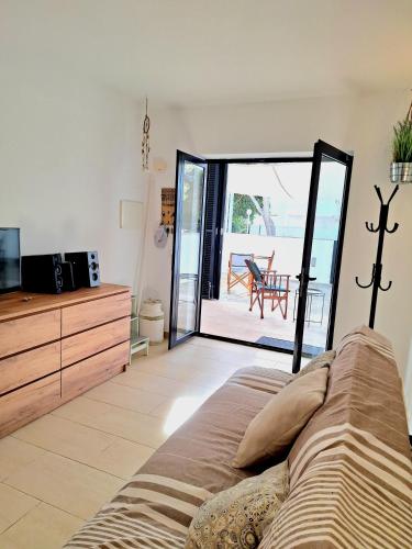 a living room with a couch and a sliding glass door at Apartamento Can Rupit Playa Santandria con jardin y piscina in Son Carrio