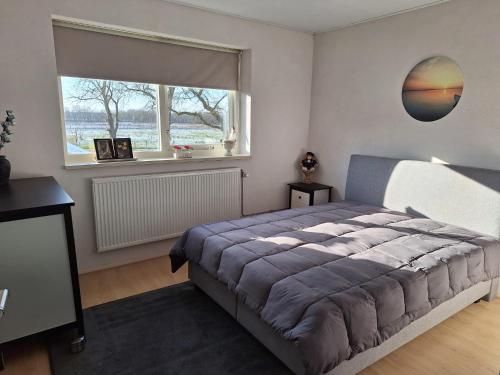 a bedroom with a large bed and a window at Liroja's Vakantiehuis in Vlagtwedde