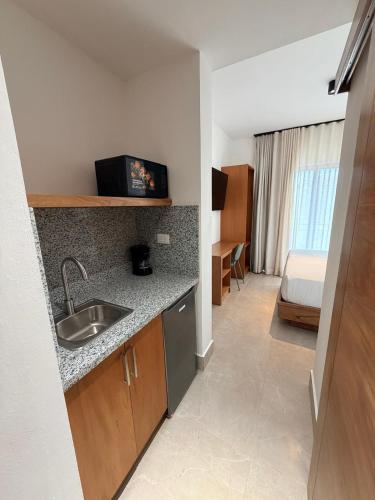 a kitchen with a sink and a room with a bed at PF Hotel in San Felipe de Puerto Plata