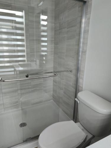 a bathroom with a toilet and a glass shower at Modern 3BR FriendlyTown Home in Paris