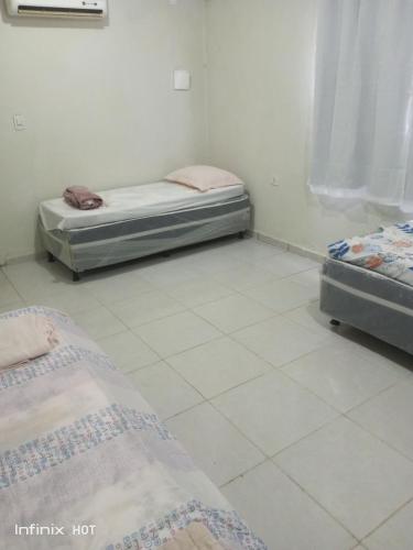 two beds in a room with white tile floors at Próximo do carnaval em Olinda in Olinda