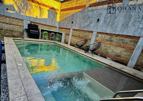 a swimming pool with two chairs in a building at Casa Ohana Morelos in Tlayacapan